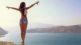 woman wearing blue hot shorts standing on rock cliff HD wallpaper