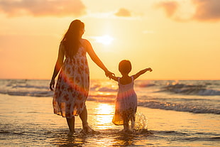 woman and girl on sea water golden hour HD wallpaper