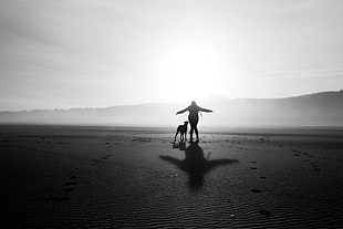 silhouette of woman and dog walking on desert under the sun HD wallpaper