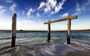time lapse photography of seashore with brown wooden port posts HD wallpaper