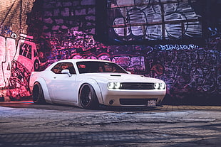 white coupe near graffiti painted wall