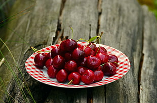 plate of red Cherries on brown wooden surface closeup photography HD wallpaper