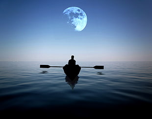 man riding on a boat alone in the sea with moon hovering above at night