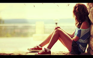 woman in blue and white shirt leaning on concrete wall