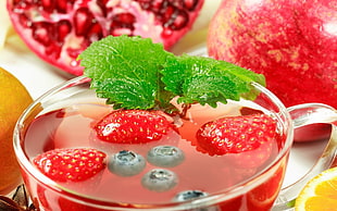 three strawberries in clear glass teacup with liquid