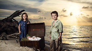 boy in dress shirt beside baby in chest and near girl in blue dress standing on beach during golden hour