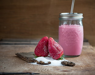 two res strawberries beside cut glass jar filled with red liquid