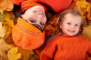 baby and mother lying on orange maple leaf surface HD wallpaper