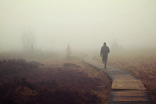 man walking on brown wooden bridge during daytime HD wallpaper