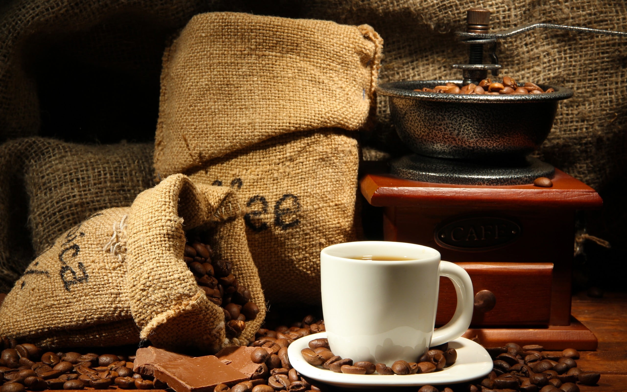 white ceramic cup and saucer set filled with coffee placed on brown wooden panel surround by lots of coffee beans