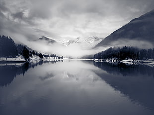 grayscale and panoramic photo of snowy mountains covered in fog