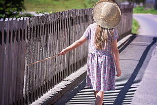 blonde haired girl wearing purple dress holding sticks during daytime