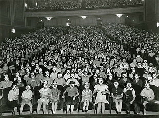 crowd of people covering face with mask sitting down in theater chairs HD wallpaper