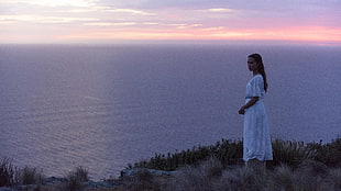 woman wearing white dress standing near ocean HD wallpaper