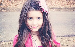 girl wearing pink top and flower hair pin looking on camera