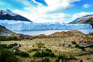 iceberg on body of water near landscape