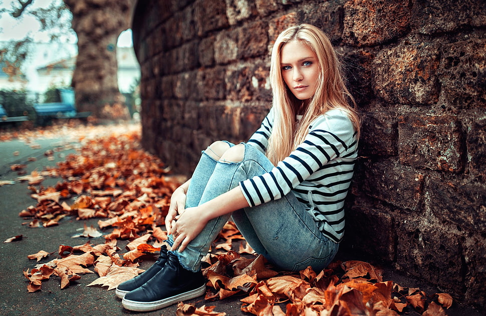 woman wearing black and white striped long-sleeved shirt leaning and sitting on dried leaves during daytime HD wallpaper