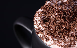 macro photography of brown coffee on black mug