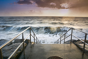 stairs with stainless steel railings in front of waves HD wallpaper