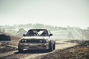 silver BMW sedan on brown concrete road under white cloudy sky during daytime