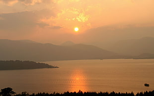 silhouette of mountains near ocean during sunset