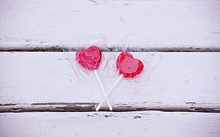 two heart-shaped lollipops on white wood surface HD wallpaper