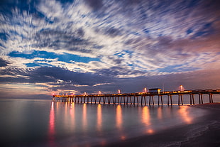 lights turned on on brown wooden dock under white clouds and blue sky during daytime, venice