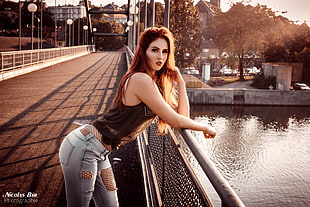 woman in black tank top and distressed grey denim jeans outfit leaning on grey metal fence on bridge during daytime HD wallpaper