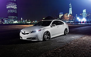 white Acura TL parked on roadway overlooking highrise buildings during night time HD wallpaper