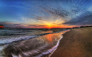 body of water under blue sky at sunrise