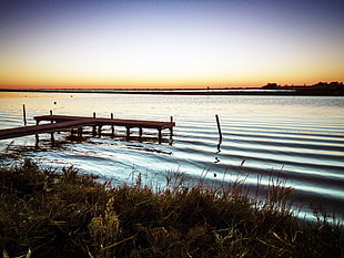 body of water near dock during sunset