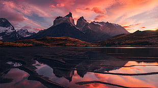 large body of water near mountain during sunset