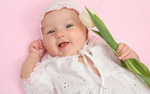 baby wearing white and pink beanie holding beige floral HD wallpaper