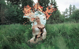 woman with umbrella kneeling on grass covered field during day