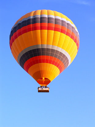orange, black, and yellow hotair balloon flying on sky, cappadocia