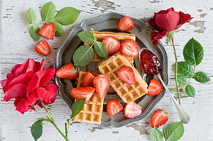 sliced strawberries in gray plate with rose flowers beside HD wallpaper