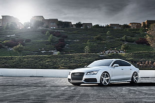 photography of silver Audi A4 near brown establishments during daytime