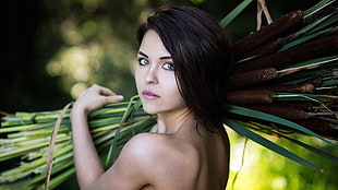 shallow focus photography of woman holding green plants