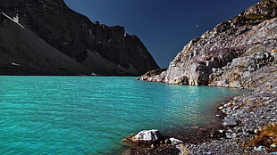 body of water near mountain hills under bluesky at daytime HD wallpaper