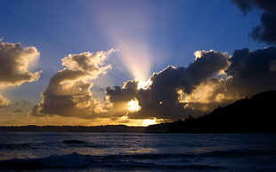 silhouette of mountain beside sea during sunset