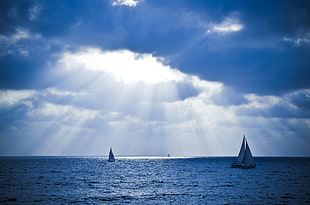 two sailboats on body of water under crepuscular rays HD wallpaper