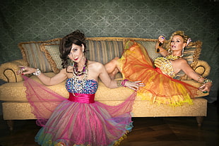 two woman wearing sweetheart neckline shear mini dresses sitting on sofa HD wallpaper