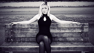 grayscale photography of woman wearing sleeveless shirt sitting on bench