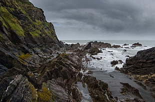 high mountain near seashore during cloudy sky HD wallpaper