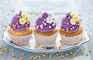 three cupcakes topped with icing on white ceramic plattes HD wallpaper