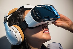 woman with white and black VR headset and white and orange headphones