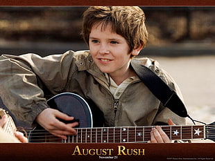 boy in gray full-zip jacket playing acoustic guitar during daytime