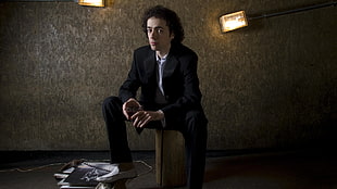 man sits wearing black suit in gray paint room HD wallpaper