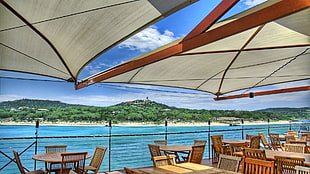 brown and white parasols with tables and chairs near sea shores during daytime