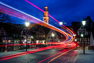 time lapse of red lights across town road during night time